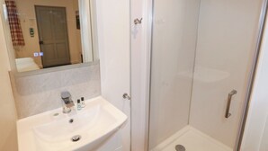 A bathroom with a white sink, mirror, and glass shower enclosure. - Chestnut (Cowbridge)