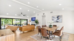 A spacious living area with a wooden dining table, leather chairs, and a large sofa.