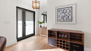 A modern interior with a herringbone-patterned cabinet, a framed abstract artwork, and a wooden floor.