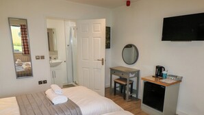 A hotel room with two beds, a desk, a mirror, a TV, and a small kitchenette. - Oak (Cowbridge)