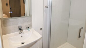 A bathroom with a white sink, a mirror, and a glass shower enclosure. - Oak (Cowbridge)
