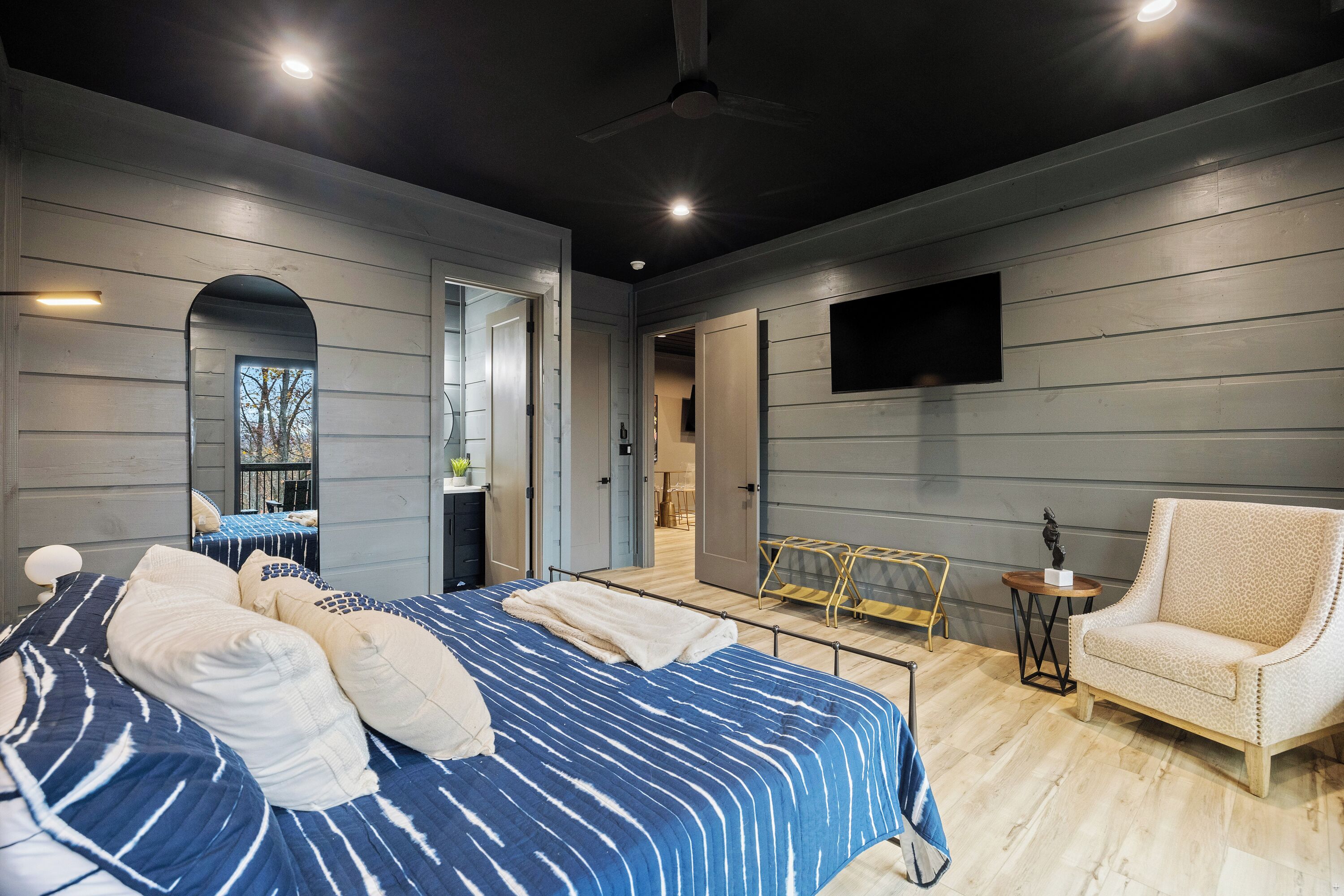 Ein Schlafzimmer mit einem Bett, einem Sessel, einem kleinen Tisch und einem an der Wand befestigten Fernseher.