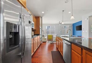 A modern kitchen with stainless steel appliances, wooden cabinets, and a central island with a sink. - 4-bedroom townhome in amazing Washington with AC, WiFi (Washington)