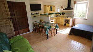 Una cocina compacta con comedor, una cama individual y un televisor montado en la pared.