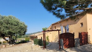 Un edificio rústico de piedra con una puerta de madera y una pérgola.