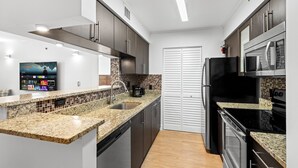 A modern kitchen with granite countertops, stainless steel appliances, and a tiled backsplash. - Cozy 1 bedroom +1 bathroom condo in enchanting Miami with AC, WiFi, Fitness room (Miami)