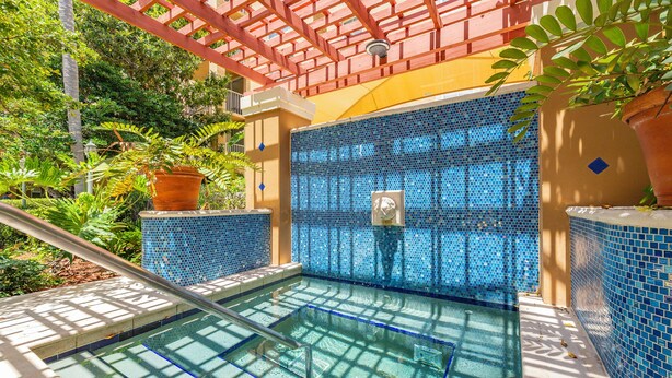 A pool with blue mosaic tiles, surrounded by greenery and a red pergola. - Cozy 1 bedroom +1 bathroom condo in enchanting Miami with AC, WiFi, Fitness room (Miami)