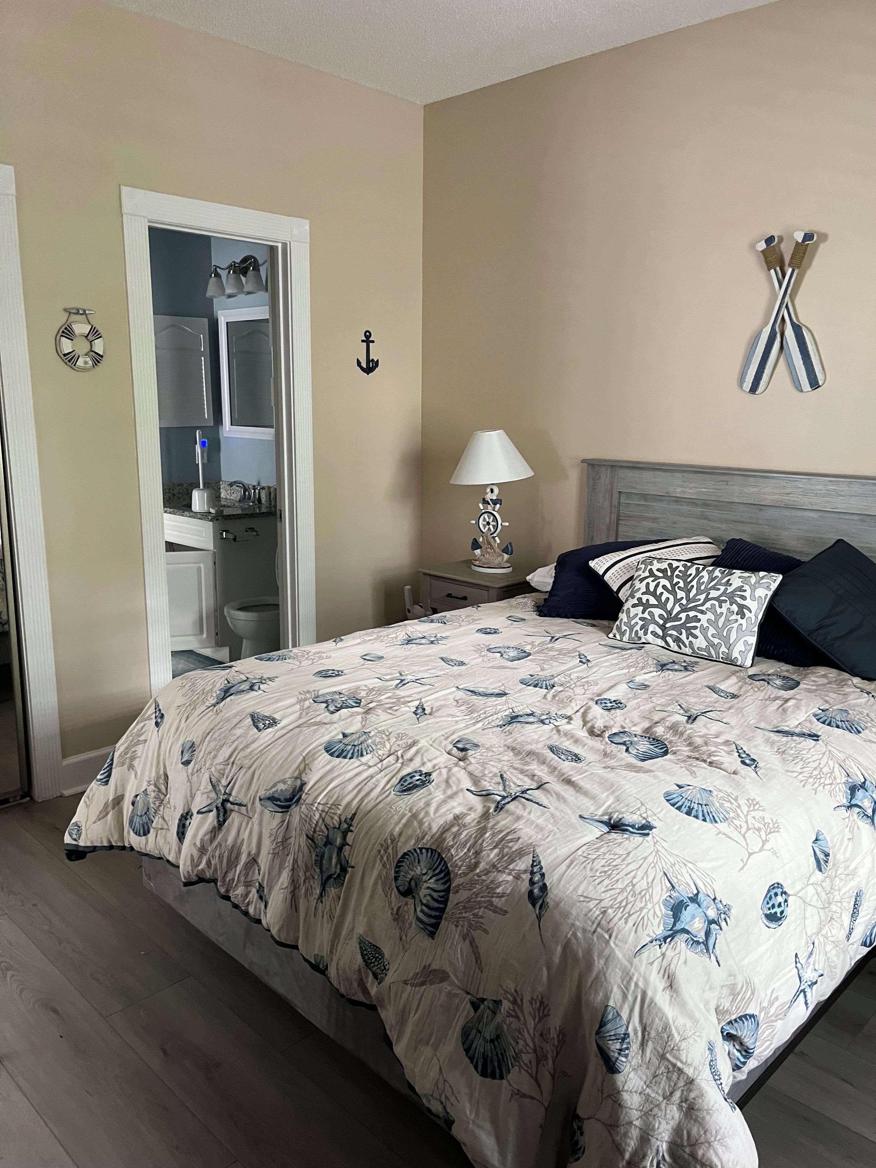Un dormitorio con cama, mesita de noche y puerta que da a un baño.