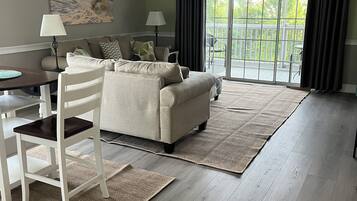 A living room with a sofa, a dining table, and a ceiling fan.