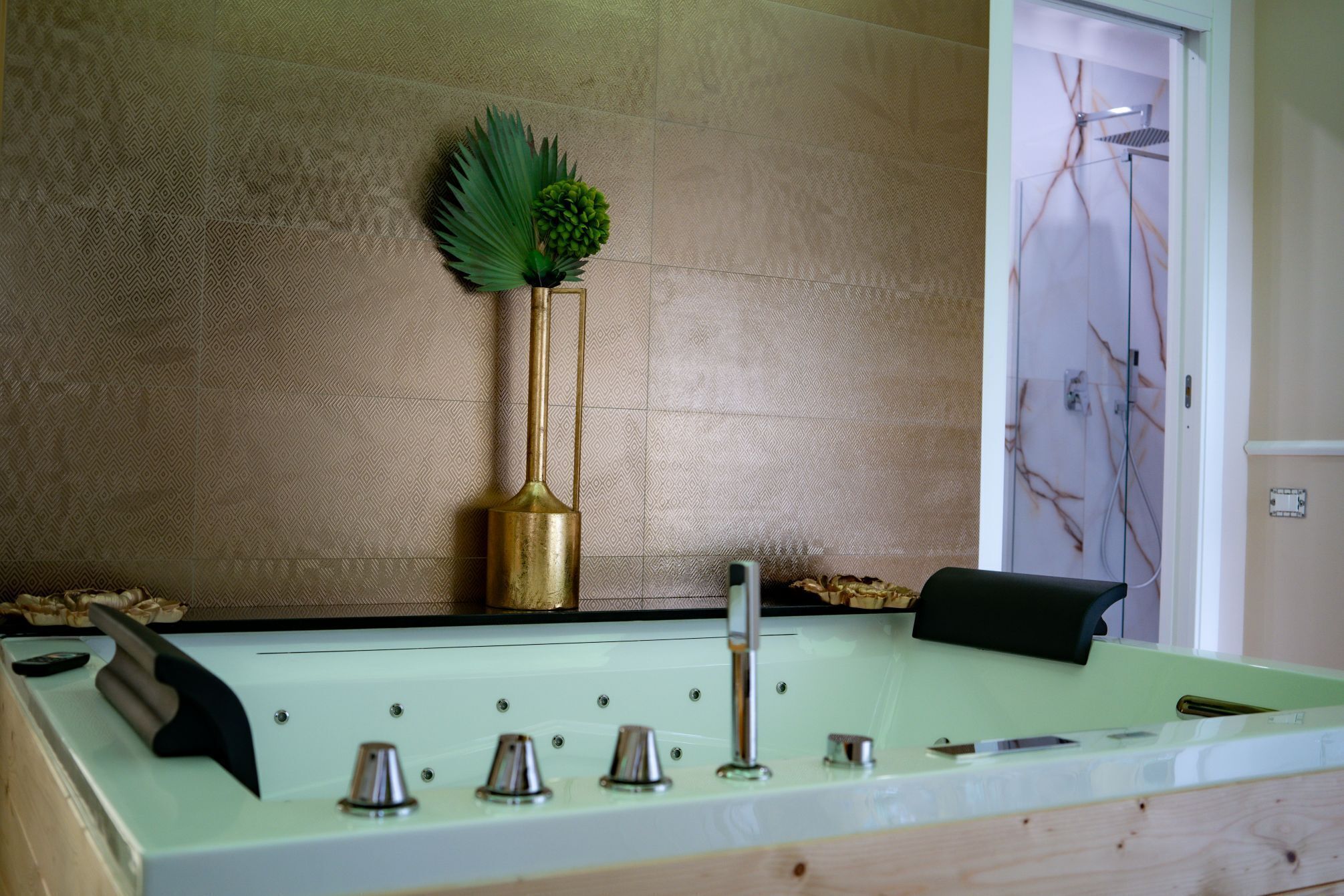 A bathroom with a patterned wall, a shower area, and a sink with various fixtures.