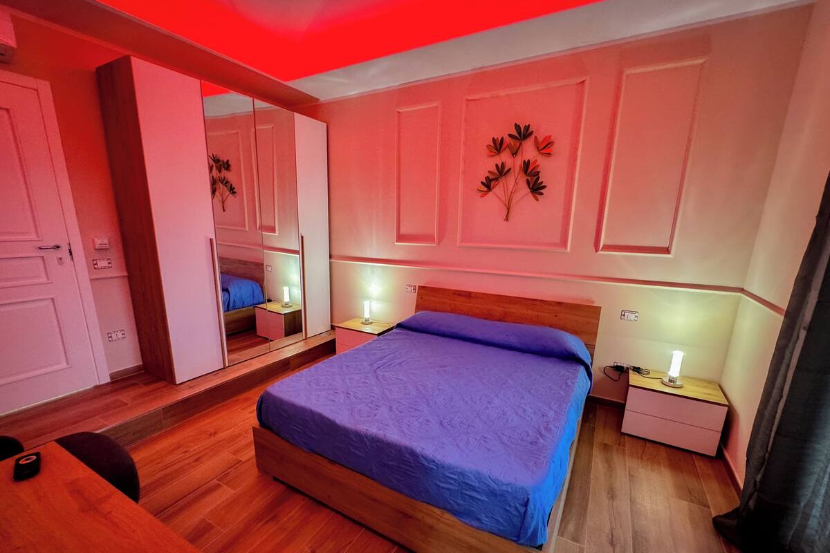 Un dormitorio con una cama de madera, un espejo, mesitas de noche con lámparas y un armario.