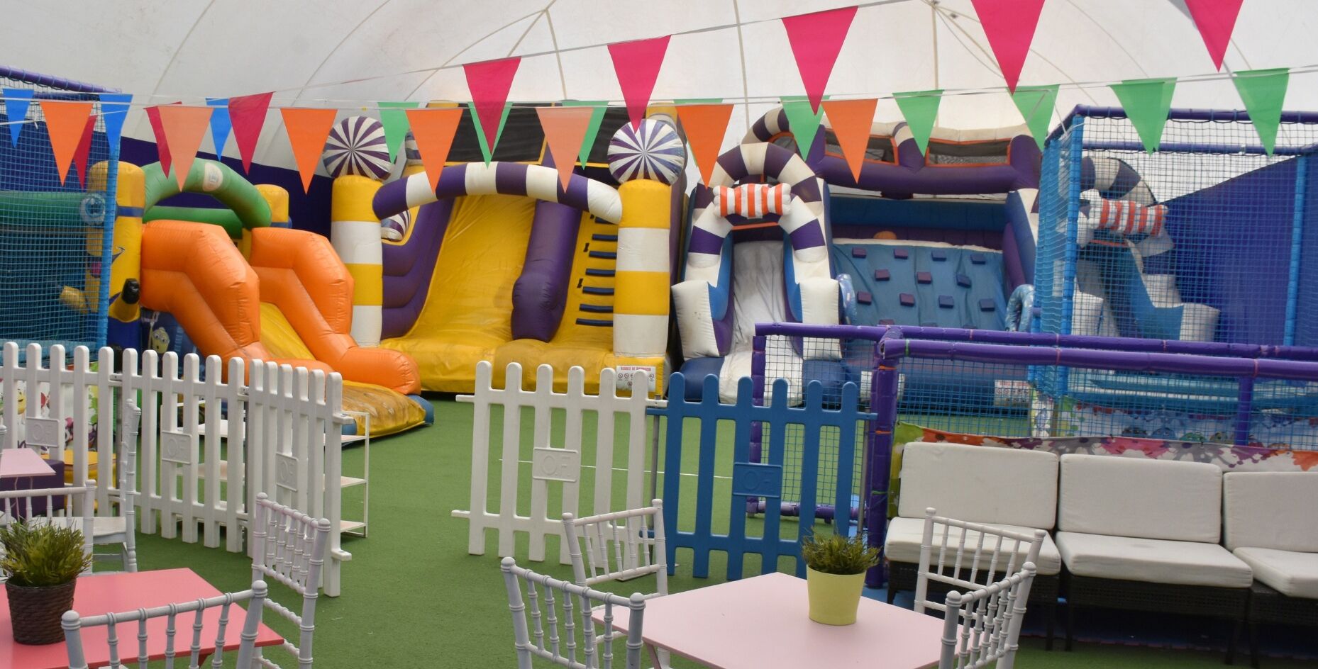 An indoor play area with inflatable slides and a fenced play zone.