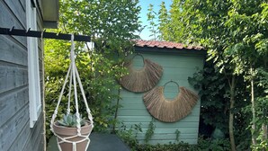 Pieni terassialue, jossa on roikkuva makrame-amppeli ja pieni pöytä.