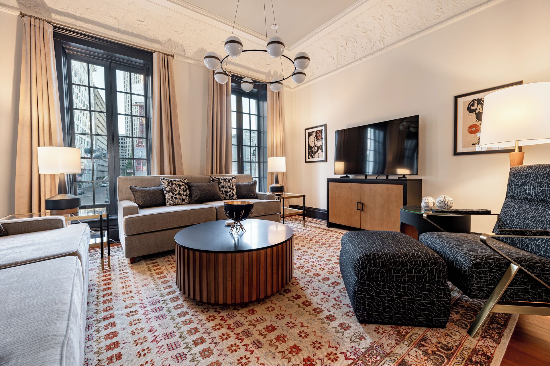 A modern living room with a sofa, ottoman, coffee table, and a TV.