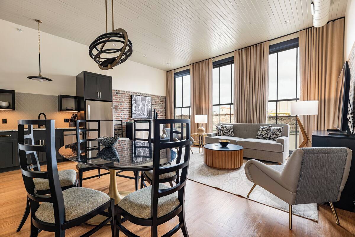 A modern living room with a dining area, a sofa, and a TV.