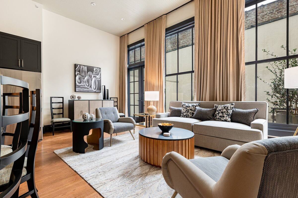 A modern living room with a sofa, chairs, a coffee table, and a dining area with a table and chairs.
