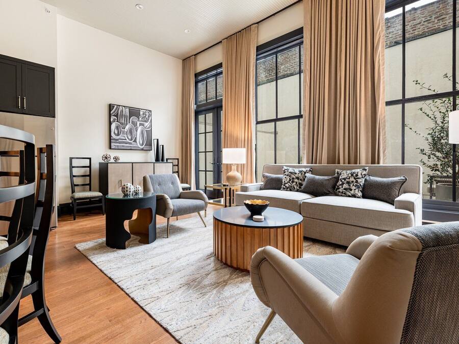 Een moderne woonkamer met een bank, stoelen, een salontafel en een eethoek met een tafel en stoelen.