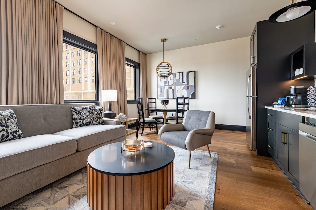 A modern living room with a sofa, armchair, coffee table, and dining area.