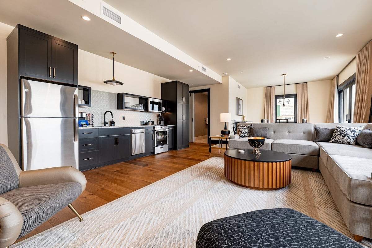 A modern kitchen with dark cabinets, stainless steel appliances, and a central island.