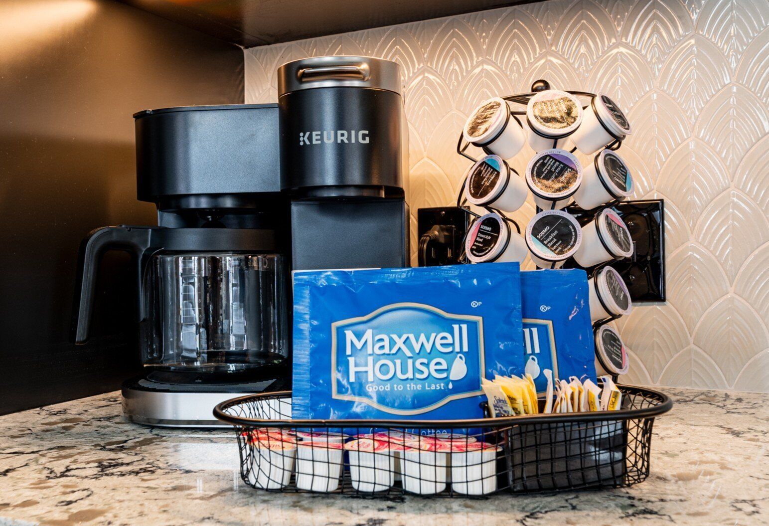 A kitchen with a Keurig coffee maker, Maxwell House coffee bags, and a basket of coffee pods.