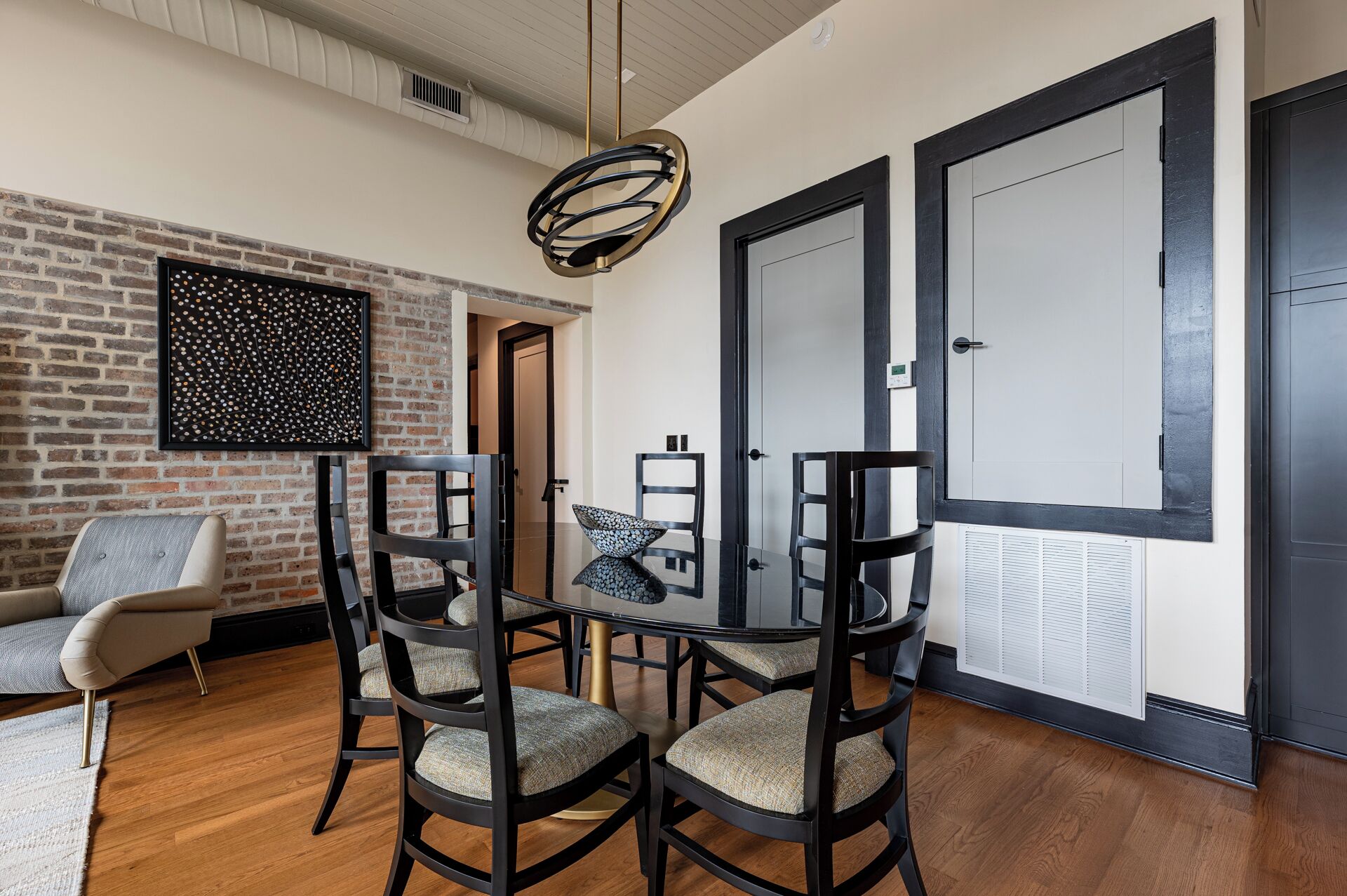 A modern dining area with a brick wall, a black-framed table, and matching chairs.