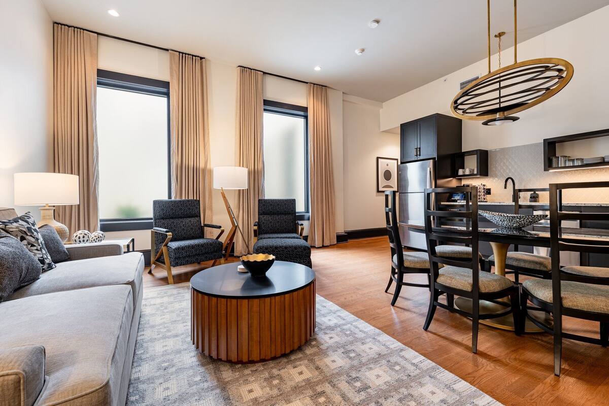 A modern living room with a sofa, two armchairs, a coffee table, and a dining area with a bar.
