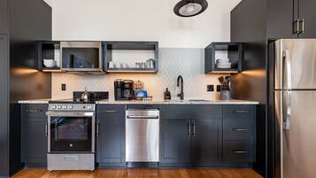 Cozinha moderna com eletrodomésticos de aço inoxidável, armários pretos e painel de fundo decorado.