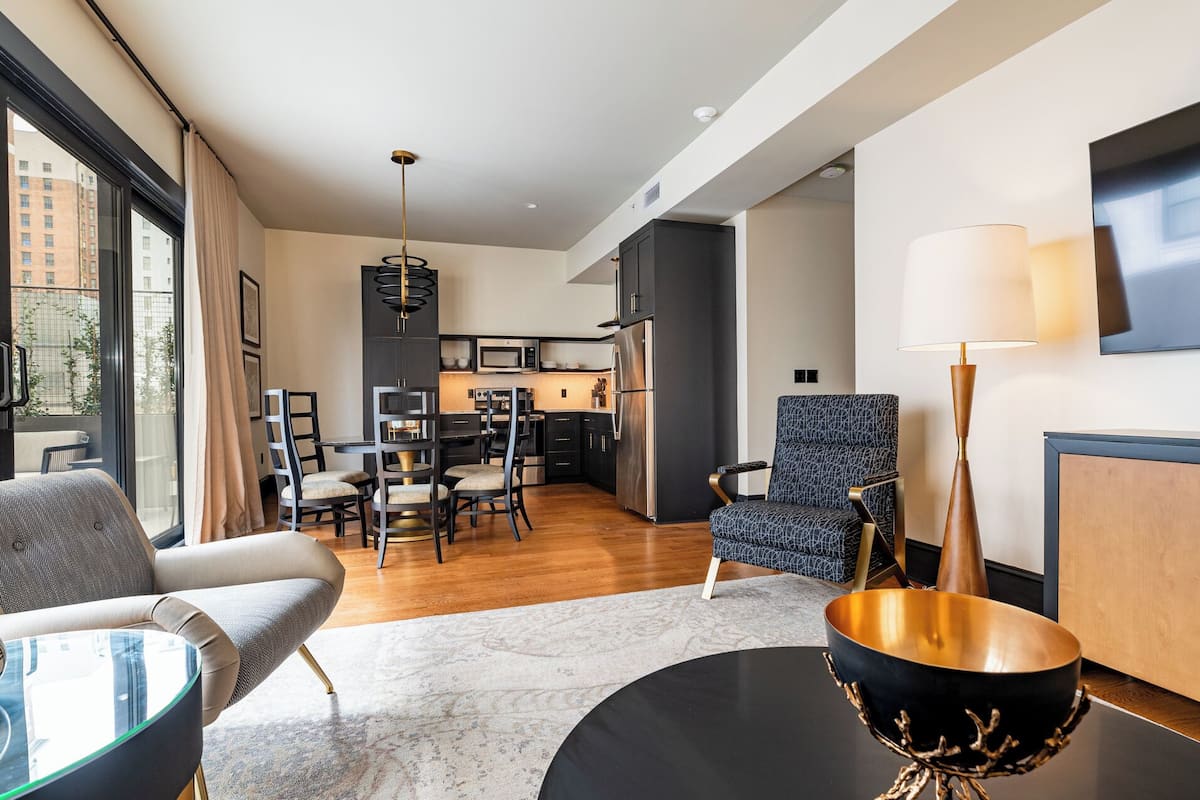 A modern living room with a dining area, a kitchen, and a view of the city.