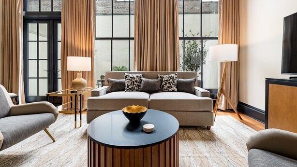 A modern living room with a sofa, two side chairs, a coffee table, and a TV. - The Mayfair (New Orleans)