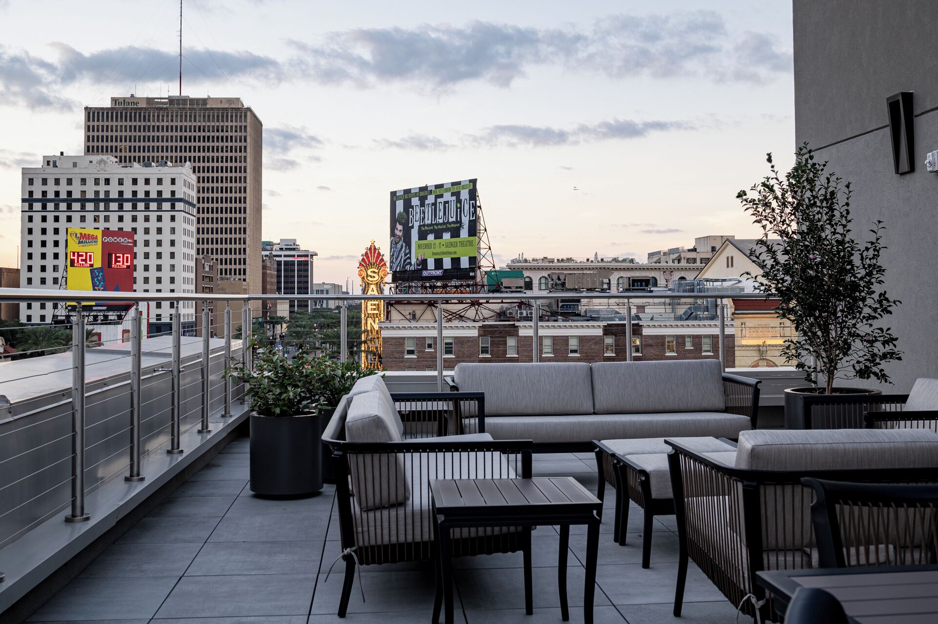 A rooftop terrace with outdoor seating, a large billboard, and city buildings in the background.