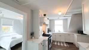 Un appartement compact et moderne, doté d’une kitchenette, d’un lit et d’une salle de bain.