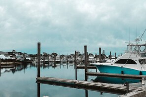 A marina with boats docked at wooden piers, calm water, and houses in the background. - Water Access 5-bed 2-bath Retreat (Hyannis)