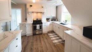 Une cuisine moderne avec des meubles blancs, une cuisinière en acier inoxydable et un tapis à carreaux.
