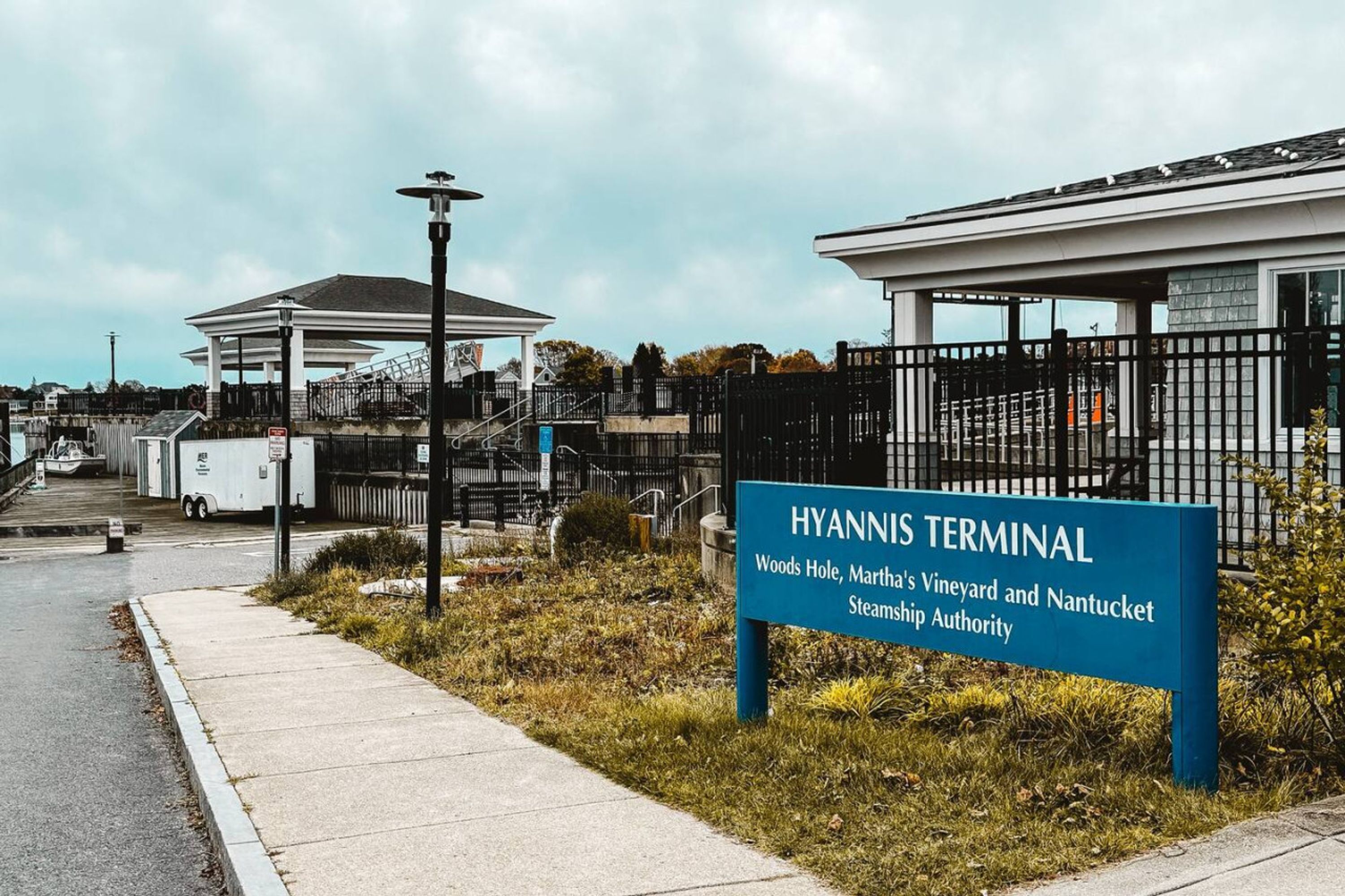 En skylt som visar vägen till Hyannis terminal, med fri sikt över det omgivande området, inklusive en byggnad och ett staket.