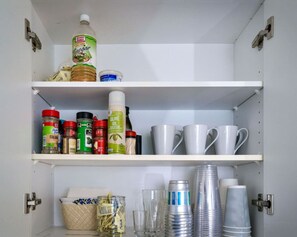 Una despensa con estantes llenos de diversos productos alimenticios, como especias, aceite de oliva y salsas.