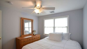 A bedroom with a bed, a dresser, a mirror, and a window. - Coastal Haven in West Dennis -15 (West Dennis)