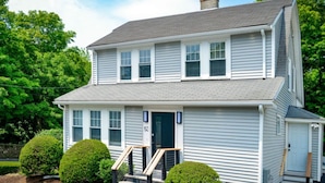 A two-story house with a front porch, a chimney, and a mailbox. - Enchanting Hidden Door Escape (Stoneham)
