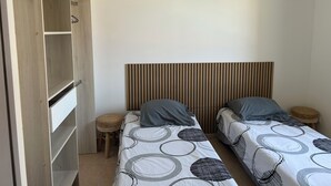 A bedroom with two single beds, a wooden wardrobe, a woven stool, and a hanging light fixture. - House in a gated community with heated swimming pool (Mouries)