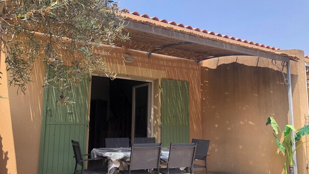 An outdoor patio with a table and chairs, a green door, and a potted plant. - House in a gated community with heated swimming pool (Mouries)