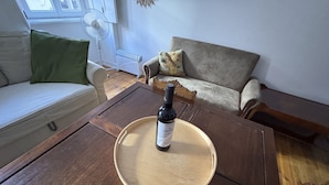 Una mesa de centro de madera con una botella de vino y un posavasos en una sala de estar.