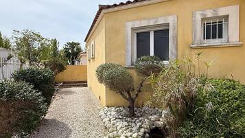 Stroll through the beautifully maintained garden, surrounded by lush shrubs and a rock border, to the entrance of this charming residence.