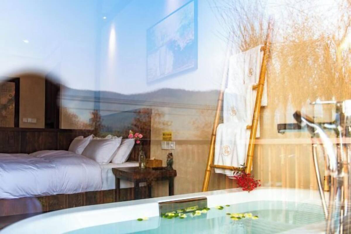 Ein Zimmer mit einem Bett, einem kleinen Tisch mit einer Vase und einer Badewanne mit Blumen.