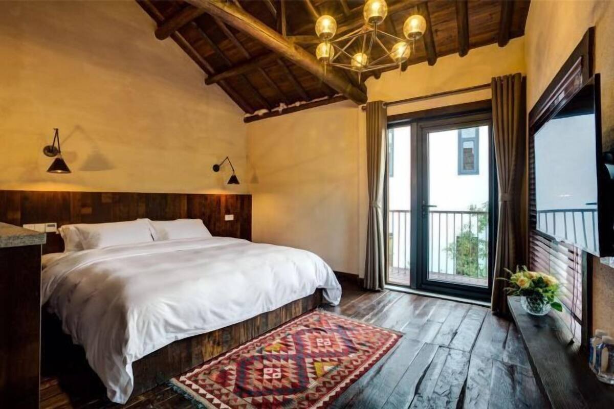 Ein Schlafzimmer mit Bett, Holzboden, Fenster und Balkon.