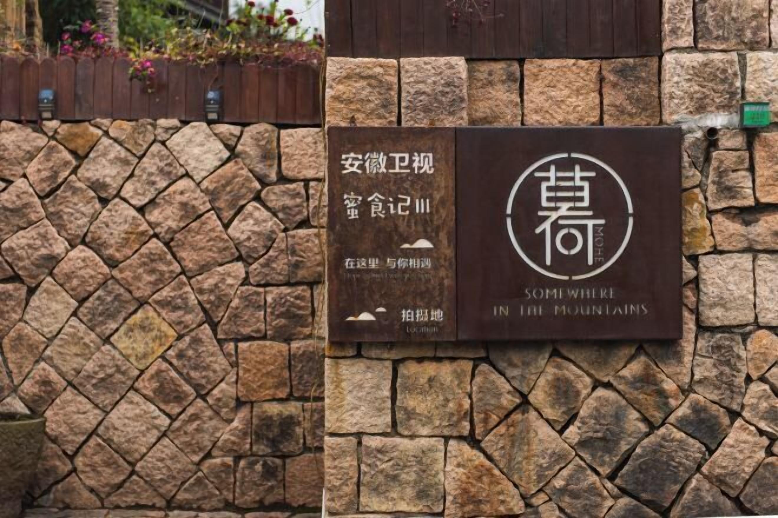 A stone wall with a sign that reads "Somewhere in the Mountains" and "In Somewhere in the Mountains."