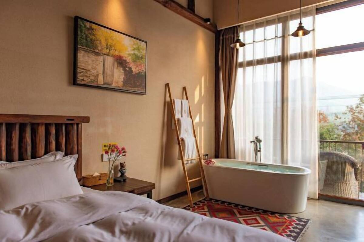 Ein Schlafzimmer mit einem großen Bett, einer Badewanne und einem Gemälde an der Wand.