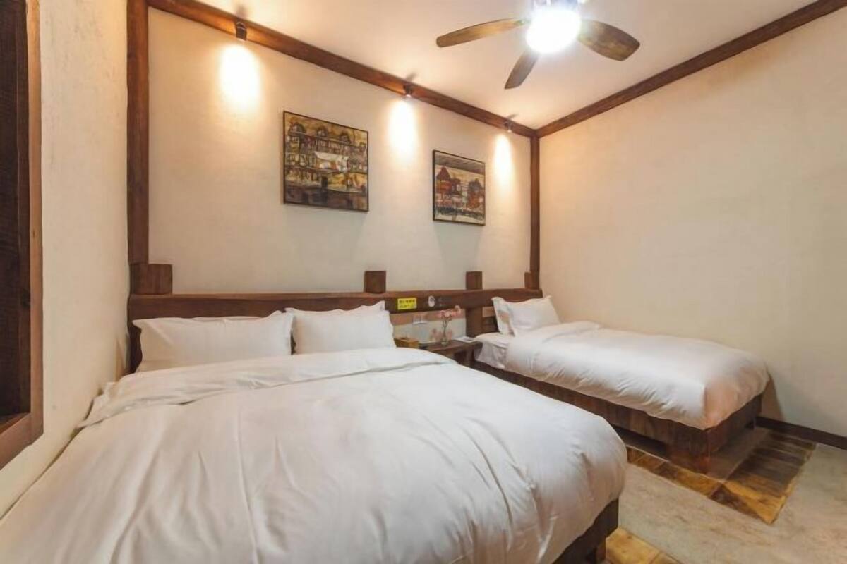 Ein Zimmer mit zwei Betten, einem Holzkopfteil, Deckenventilator und zwei Wandleuchten.
