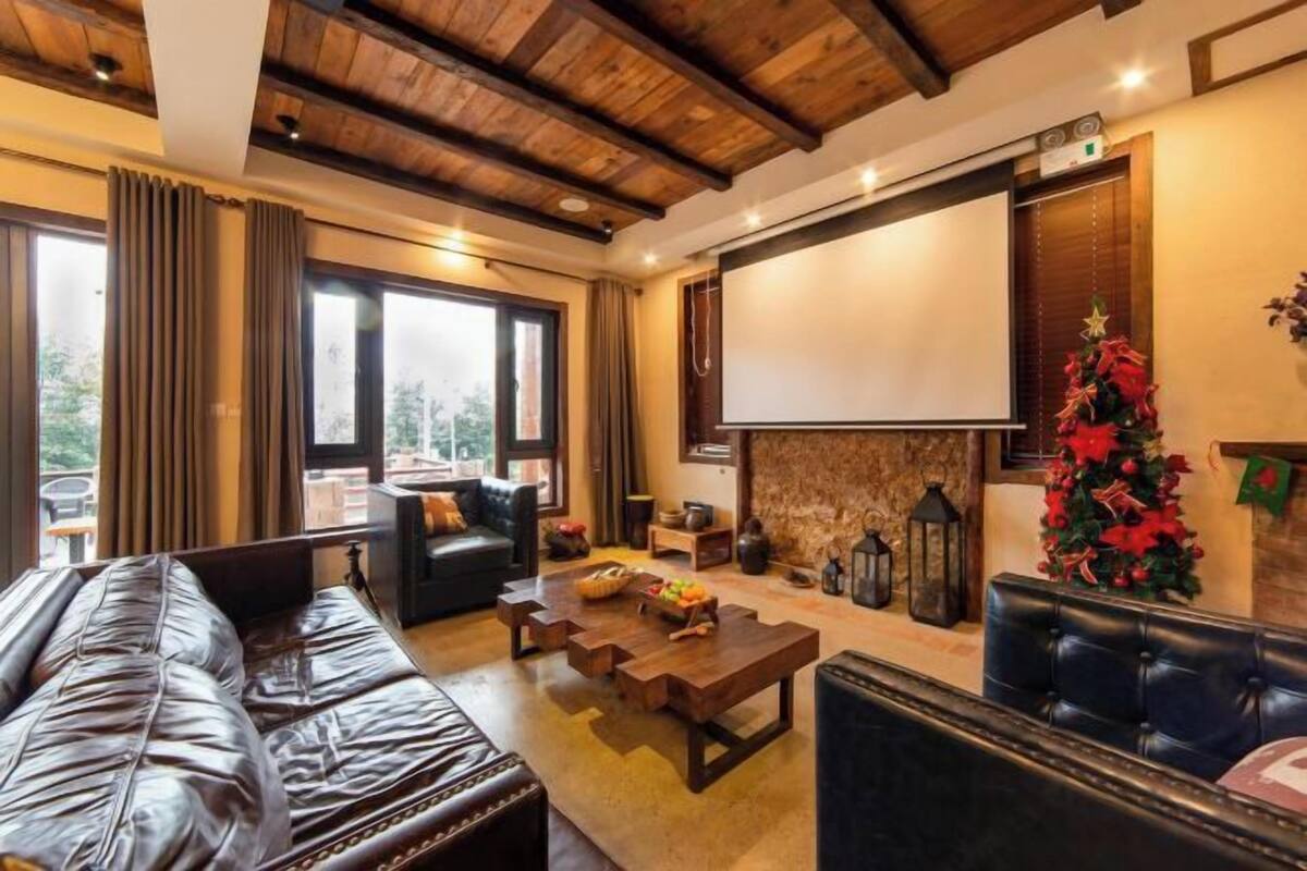 Ein gemütliches Wohnzimmer mit Kamin, Ledersofas, einem Couchtisch und einem Weihnachtsbaum.
