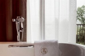 Een badkamer met een bad, een douchekop en een handdoek met een logo.