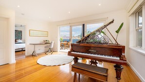 Une pièce spacieuse comprenant un grand piano, un coin repas et une grande fenêtre donnant sur l’extérieur.