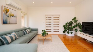 Un salon avec un canapé, une table basse, un téléviseur et de grandes fenêtres.